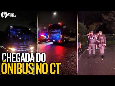 Ônibus do Corinthians chegando ao CT Dr. Joaquim Grava com viaturas policiais ao redor.